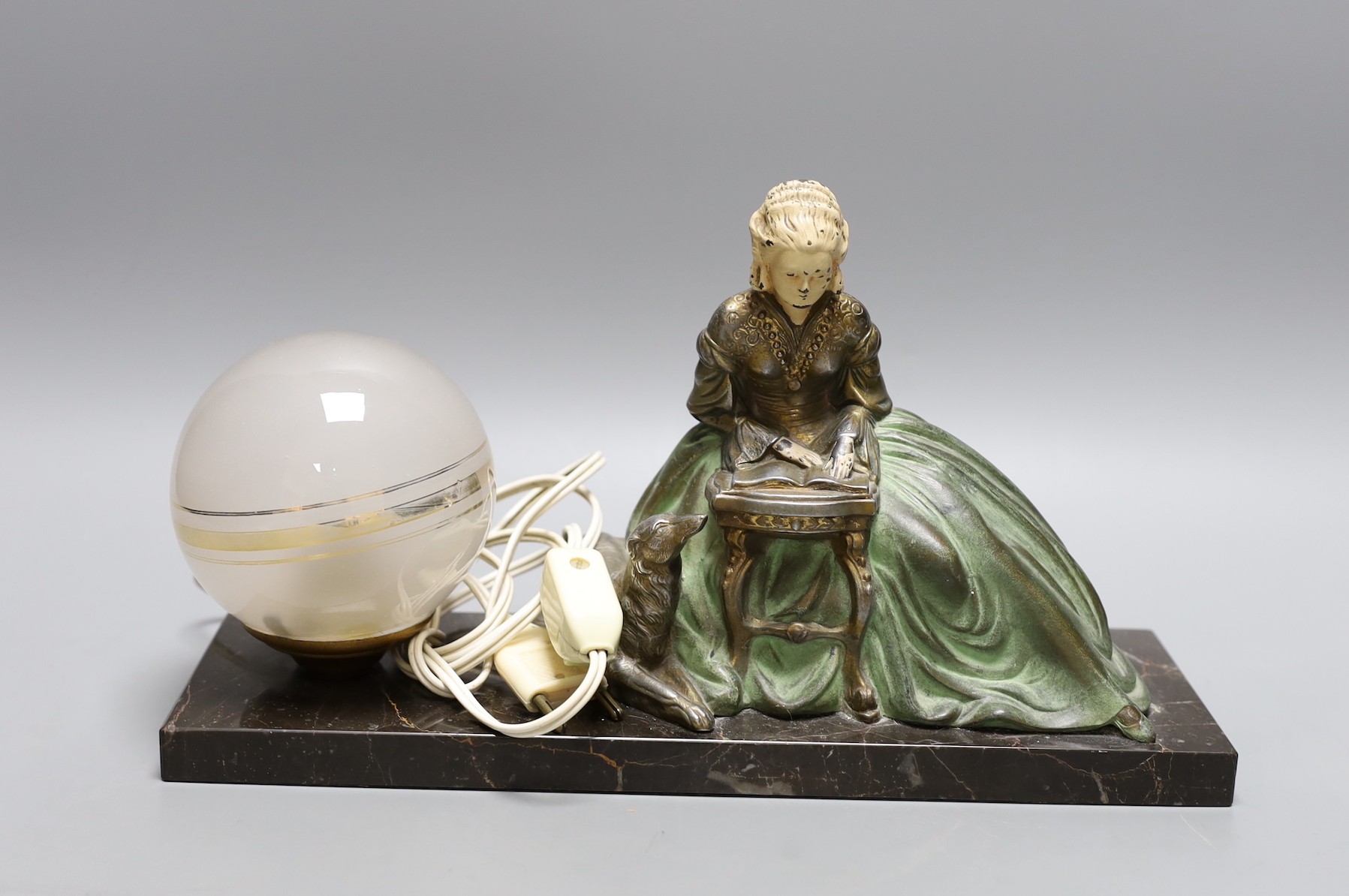 A French 1930's lamp with a seated female reading beside a laying loyal hound on marble plinth base, signed R. Miandres, 32cm wide